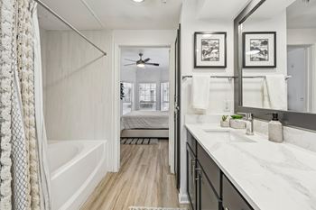 A bathroom with a white tub and marble countertops.